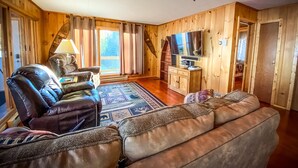 A cozy living room with a leather sofa, a television, and a wooden interior.