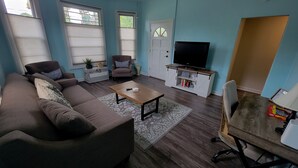 A living room with a sofa, armchairs, a coffee table, a TV, and a cabinet. - Historic 3 bed, 2bath Bungalow Minutes from IAH with Backyard Putting Green! (Humble)