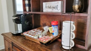 A coffee station with a coffee maker, a tray of yogurt cups, a milk carton, and a mug rack. - Historic 3 bed, 2bath Bungalow Minutes from IAH with Backyard Putting Green! (Humble)