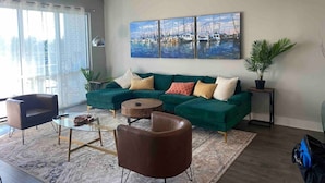 Ein modernes Wohnzimmer mit einem grünen Sofa, einem runden Couchtisch und einem Deckenventilator.