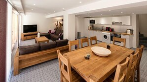 Een moderne woonkamer met een bank, televisie en een eethoek.