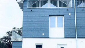 Ein zweistöckiges Wohngebäude mit Balkon, Eingangstür und sichtbarer Garagenöffnung.
