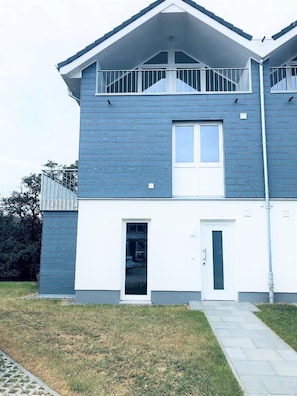 Een woonhuis met twee verdiepingen, een balkon, een voordeur en een zichtbare garage.