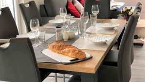 Ein Esstisch, gedeckt mit Tellern, Gläsern und einem Croissant.