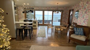 A cozy kitchen with a view of the water, a dining area with chairs, and a living room with a sofa and a decorative pillow. - Private Elk Lake Cottage minutes from Elk Rapids (Kewadin)