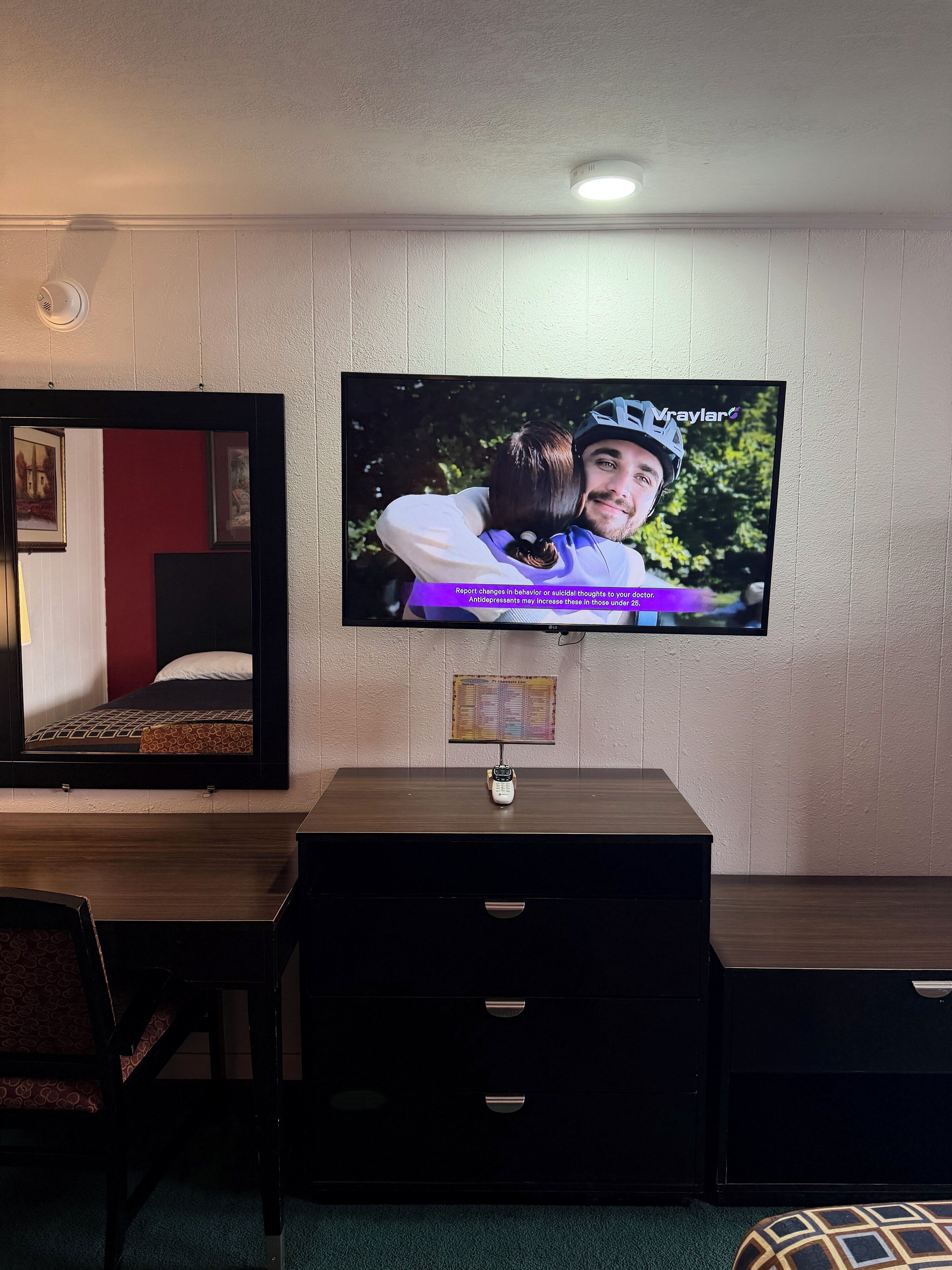 A television mounted on a wall displaying a scene with two people embracing.