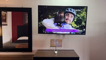 A television mounted on a wall displaying a scene with two people embracing.