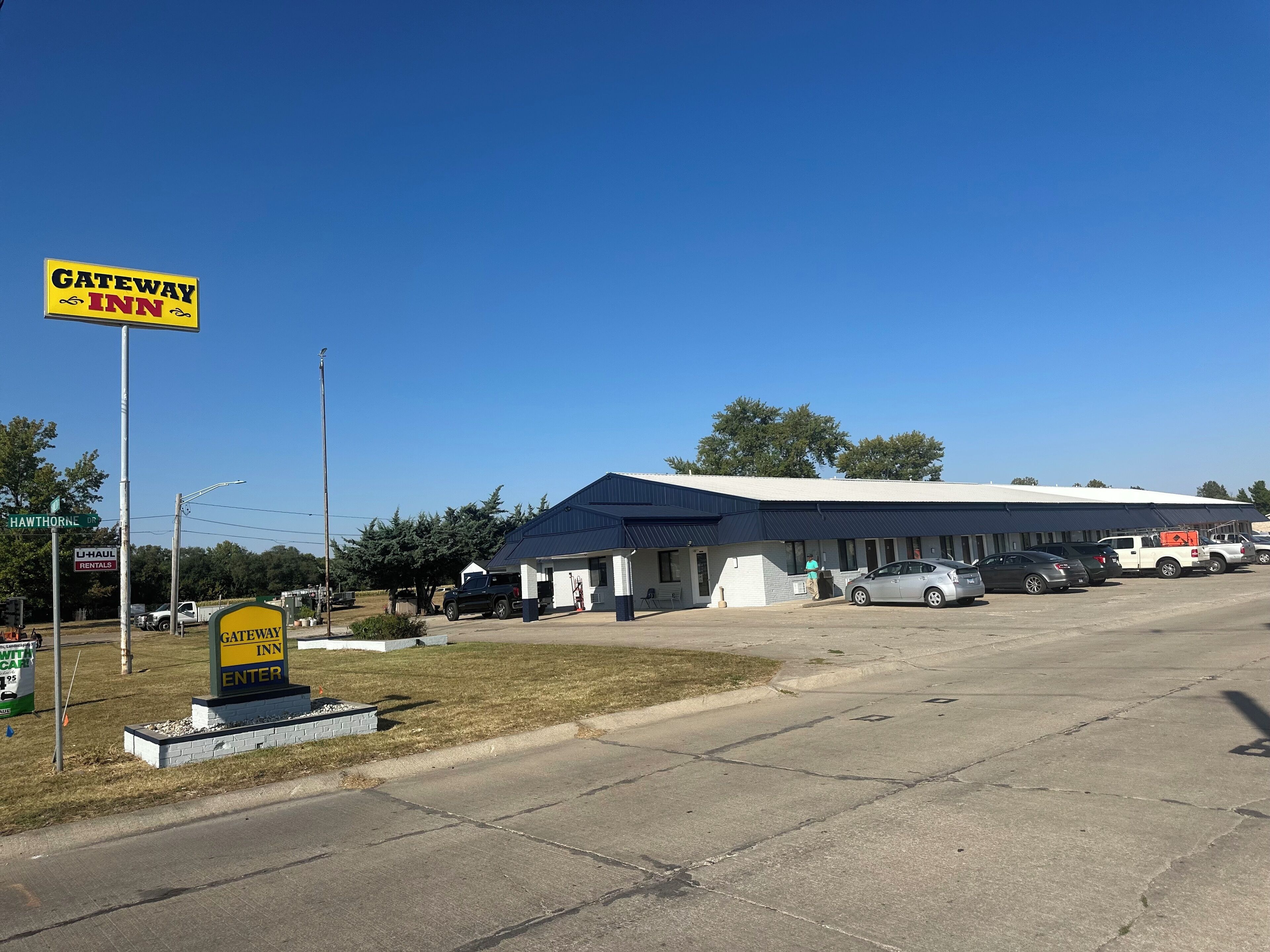 A Gateway Inn motel with a large parking lot, a U-Haul rental sign, and a clear blue sky.