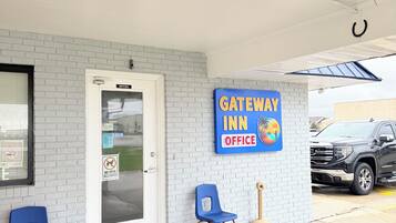 Ufficio del Gateway Inn con facciata in mattoni bianchi, un'insegna blu e due sedie blu all'esterno.