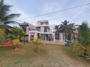 A modern multi-story residential building with a covered outdoor seating area and a swimming pool.