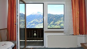 Une chambre avec un lit, une table et une vue sur les montagnes par la fenêtre.