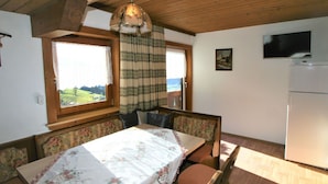 A cozy dining area with a wooden table, floral tablecloth, and a view of the outdoors through a window. - Lovely apartment in villa for 10 guests with WIFI, TV, balcony and pets allowed (Hart Im Zillertal)