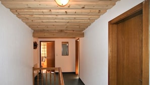 A narrow hallway with wooden beams on the ceiling, a wooden staircase, and a door on the right. - Lovely apartment in villa for 10 guests with WIFI, TV, balcony and pets allowed (Hart Im Zillertal)