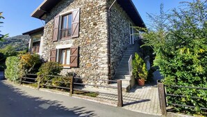 A stone house with a balcony, wooden shutters, and a paved entrance. - Nice apartment for 4 people with WIFI, TV, balcony, pets allowed and panoramic view (Gravedona)