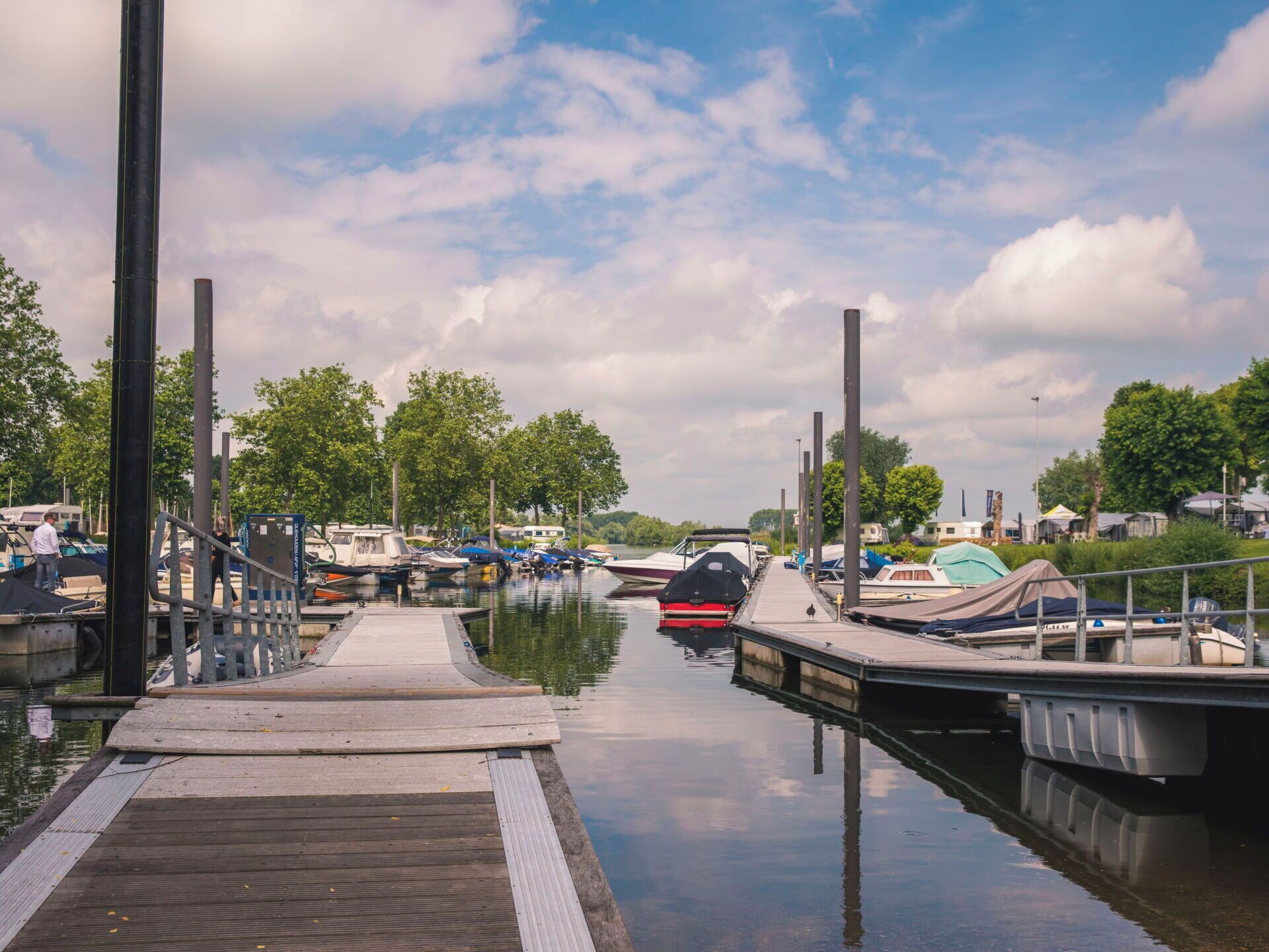 A marina with docked boats, a wooden pier, and a calm water body.
