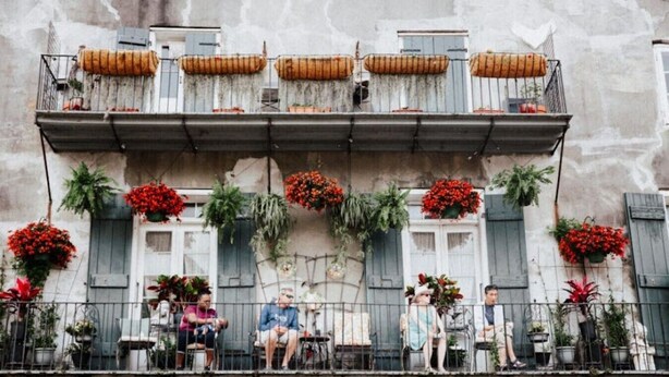 A balcony with potted plants and flowers, a railing, and a building facade. - Luxury 2 Bed 2 Bath Condo In Bywater with Pool! (New Orleans)