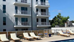 A modern hotel with a pool area, featuring multiple balconies and lounge chairs. - Luxury 2 Bed 2 Bath Condo In Bywater with Pool! (New Orleans)