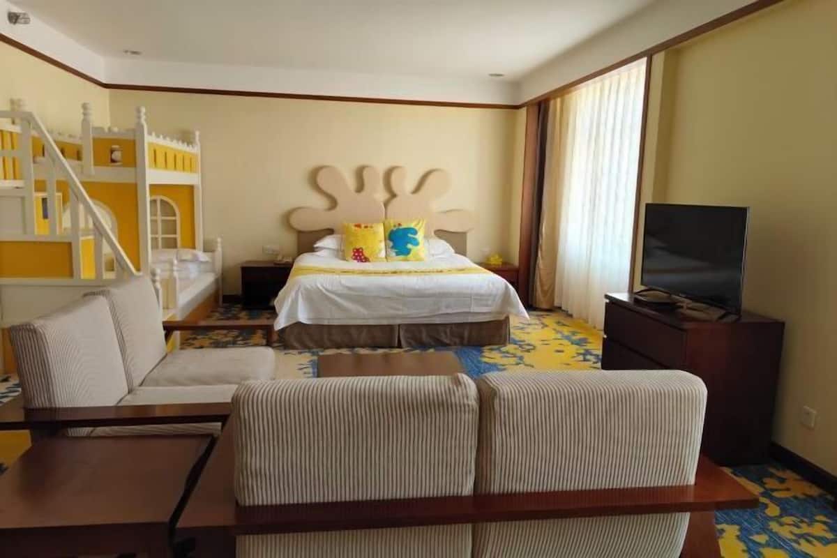 A hotel room with a bed, a TV, a sofa, and a staircase.