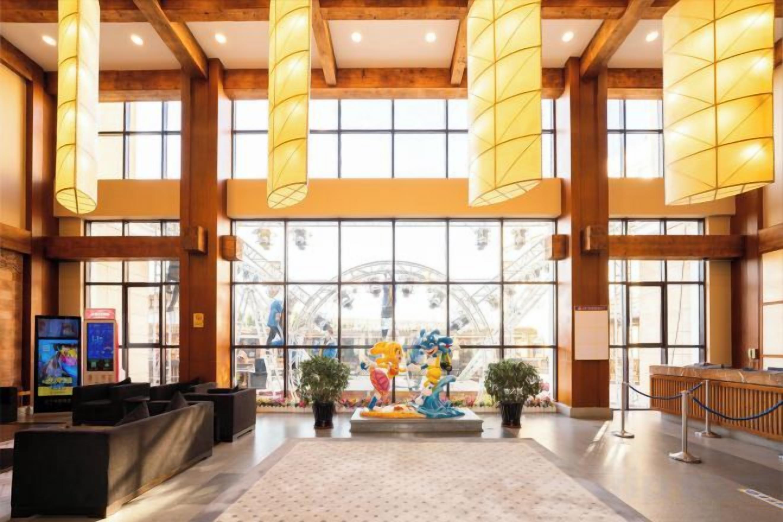 Een ruime lobby met hoge plafonds, grote ramen en een centrale decoratieve fontein.