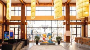 Een ruime lobby met hoge plafonds, grote ramen en een centrale decoratieve fontein.