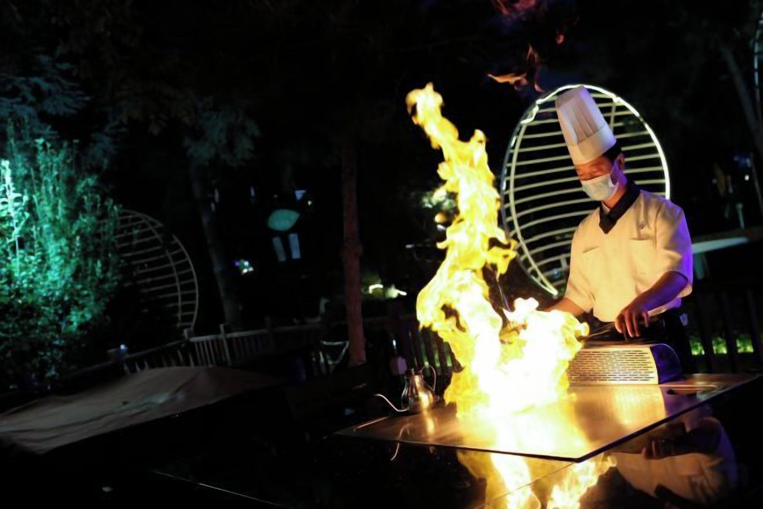 Un chef cuisinier qui réalise une démonstration avec du feu sur une scène.
