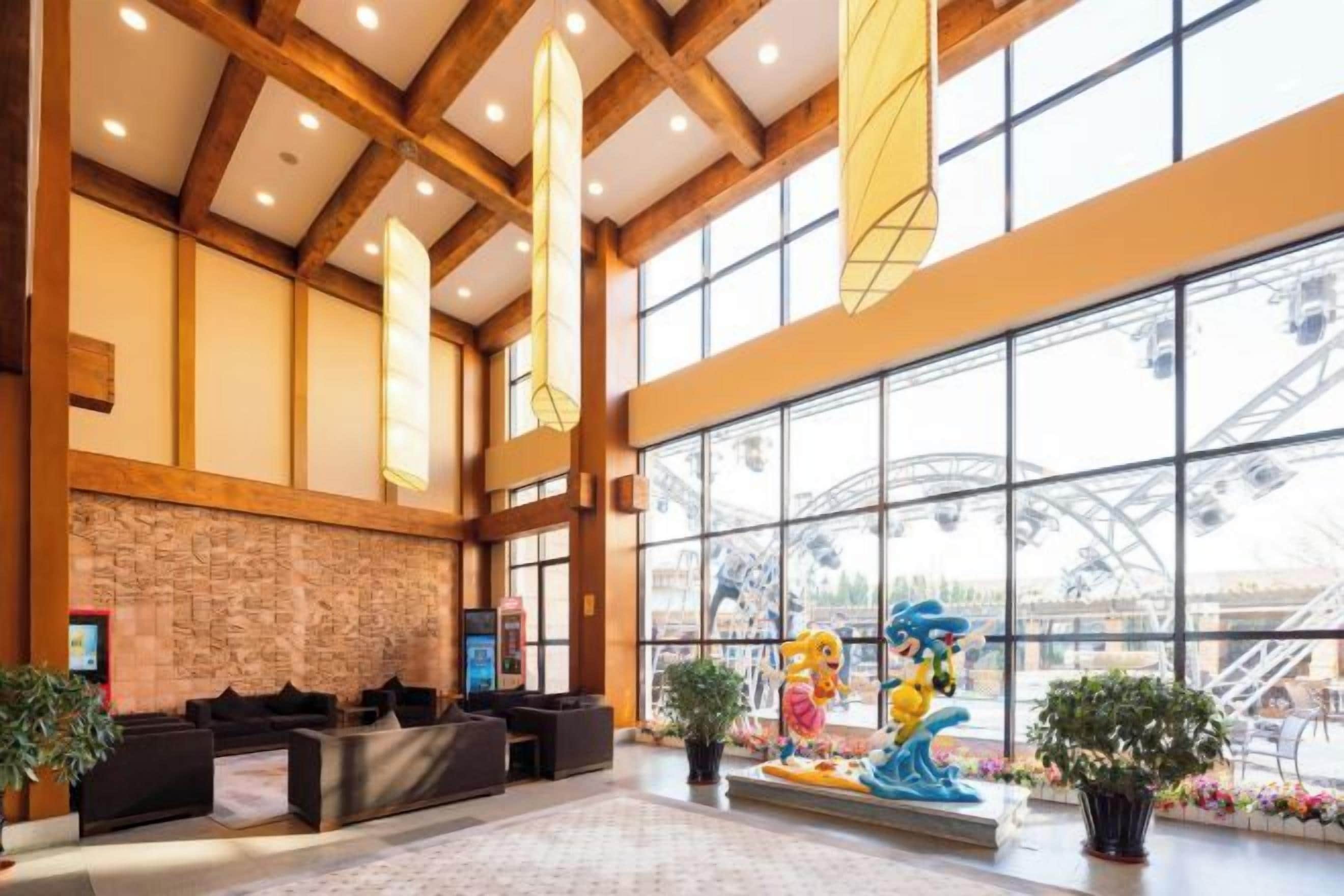 A lobby with a reception desk, seating area, and large windows with a view of a roller coaster.