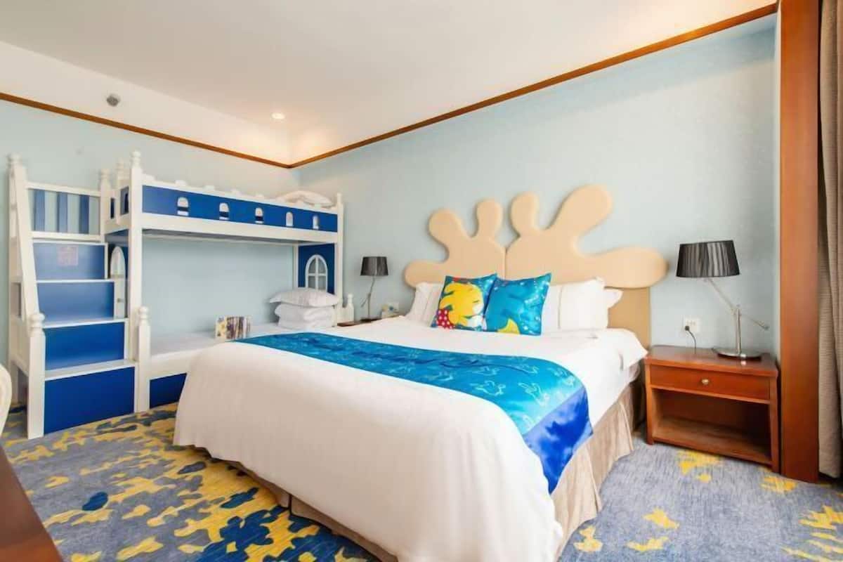 A hotel room with a bunk bed, a desk, and a nightstand.