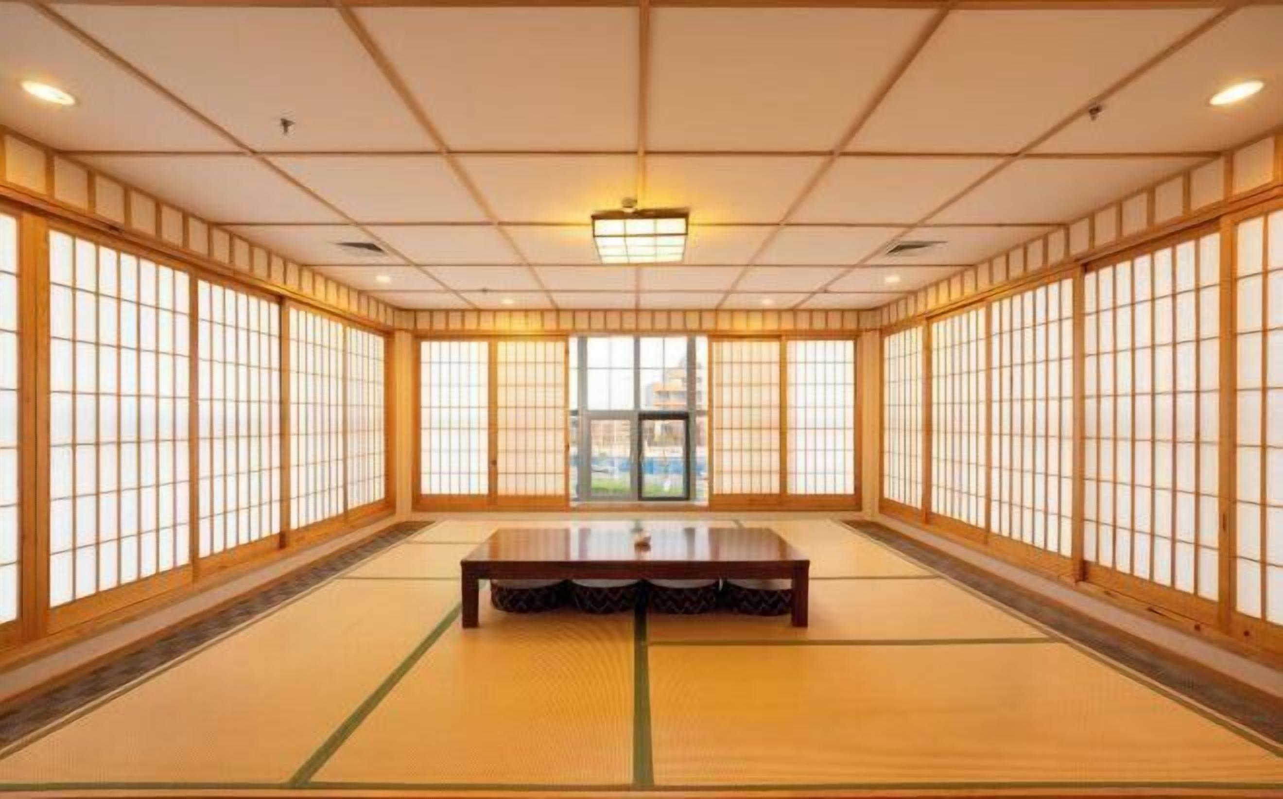 A traditional Japanese room with tatami flooring, sliding doors, and a central tatami mat table.