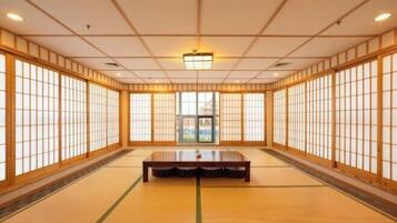A traditional Japanese room with tatami flooring, sliding doors, and a central tatami mat table.