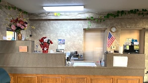 A reception desk with a clock, an American flag, and a calendar. - Coachman's Inn Motel (Wynne)