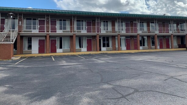 A motel with a two-story structure, multiple rooms, and a parking lot.