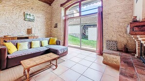 Ein gemütliches Wohnzimmer mit Steinwand, Holzboden und einem großen Fenster mit Vorhängen.