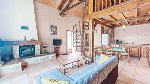 Ein großzügiger Wohnbereich mit Kamin, Fernseher und Essbereich mit Holzzmöbeln.