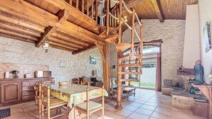Ein rustikales Interieur mit einer Holztreppe, einem Essbereich mit Tisch und Stühlen sowie einer Küche mit einfachen Geräten.