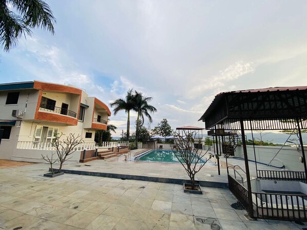 Zona residencial con piscina, un espacio de estar techado y vista al mar.