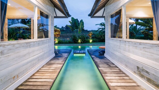 Una casa moderna con terraza de madera que da a una piscina.