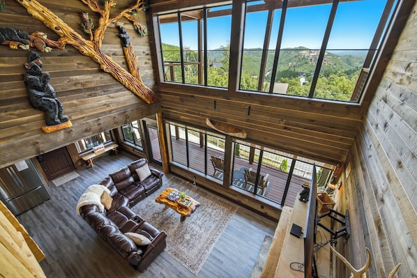 A spacious living area with a large window, a leather sofa, and a wooden ceiling.