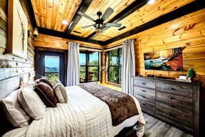 A bedroom with a bed, a ceiling fan, a TV, and a dresser.