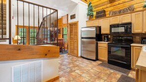 Eine Küche mit Holzschränken, einem Edelstahlkühlschrank, einem schwarzen Backofen und einer Mikrowelle.