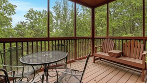 Eine Holzterrasse mit Tisch, Stühlen und einer Bank, sowie einem Deckenventilator.