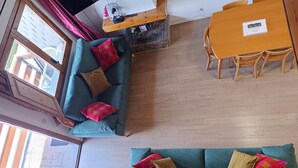 Un salon avec un canapé de couleur turquoise, une table à manger en bois et un escalier.