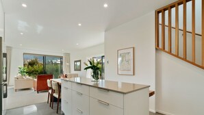 A modern kitchen with a large island, white cabinetry, and a wooden staircase. - Jacks Point Family Retreat - Jacks Point Home (Queenstown)