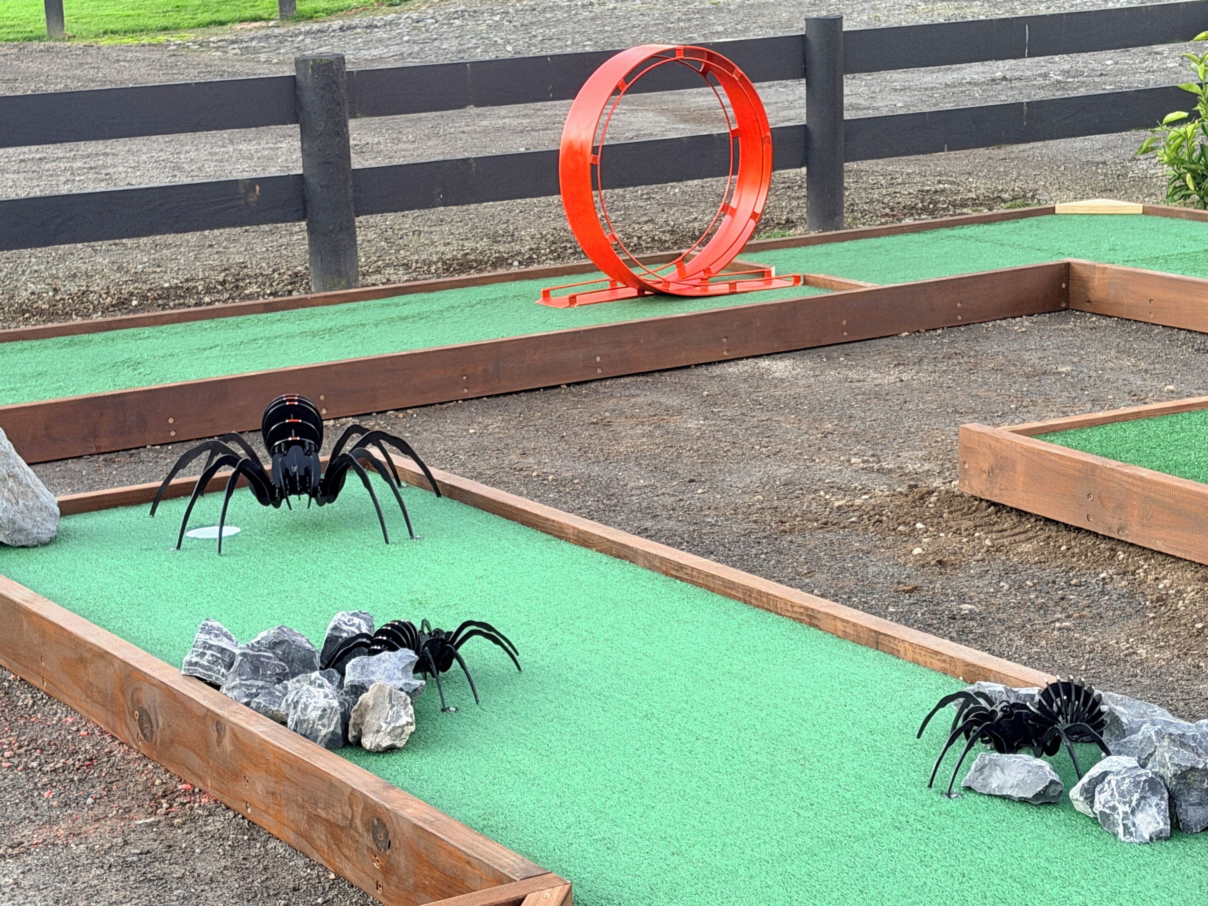 A miniature golf course with wooden bunkers and a red circular obstacle.