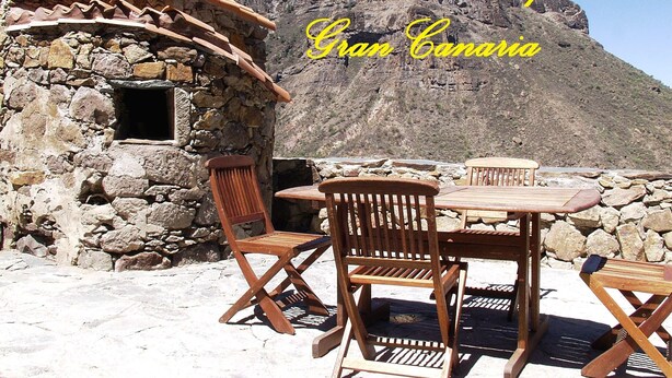A stone building with a tiled roof and wooden furniture outside. - Rural House Pepita La De Las Flores (Provincia de Las Palmas)