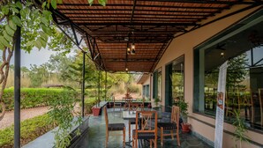 Un patio al aire libre con una zona de estar cubierta, plantas en macetas y vistas del jardín circundante.