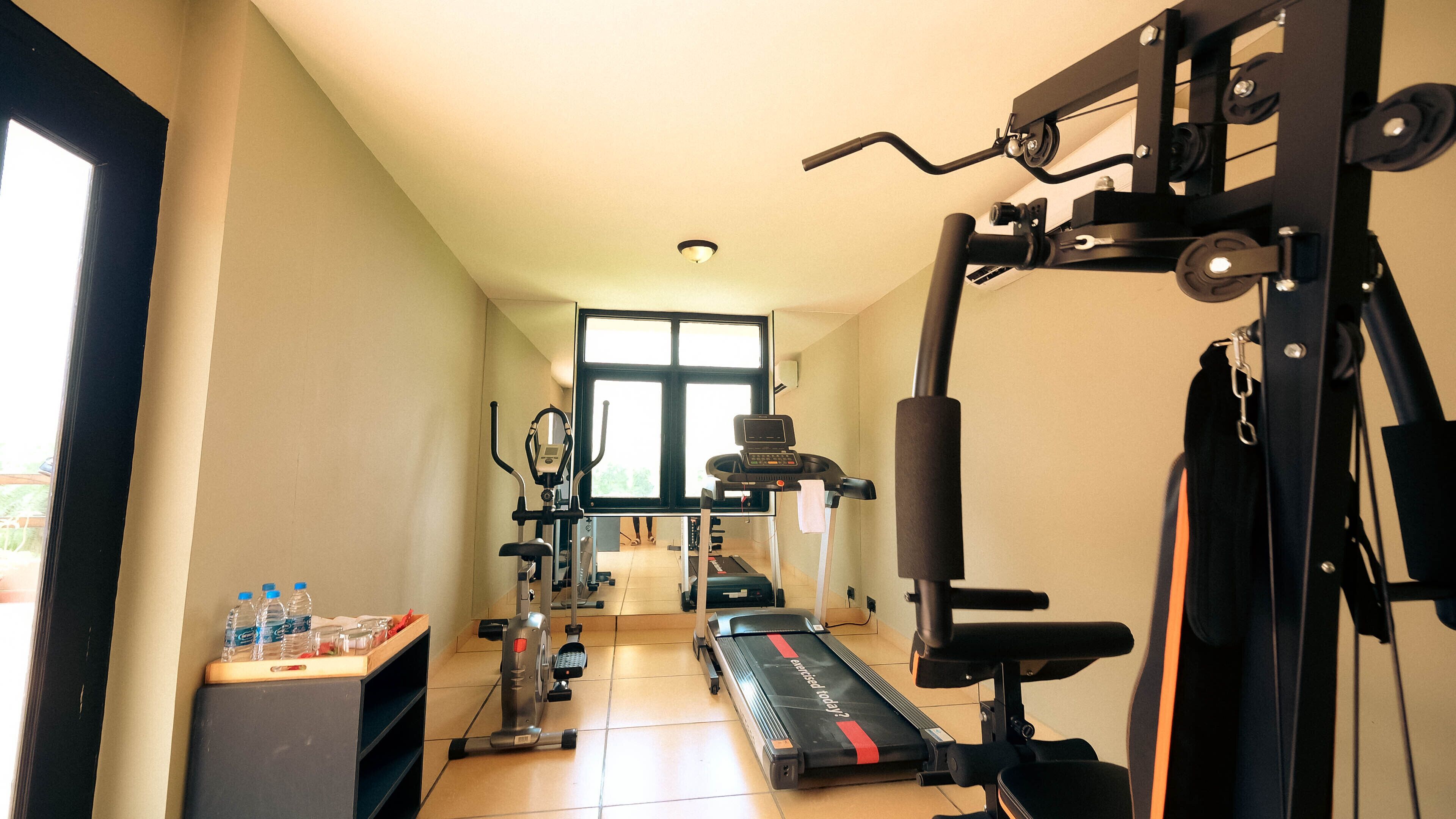 A home gym with exercise equipment, a treadmill, and a window providing natural light.