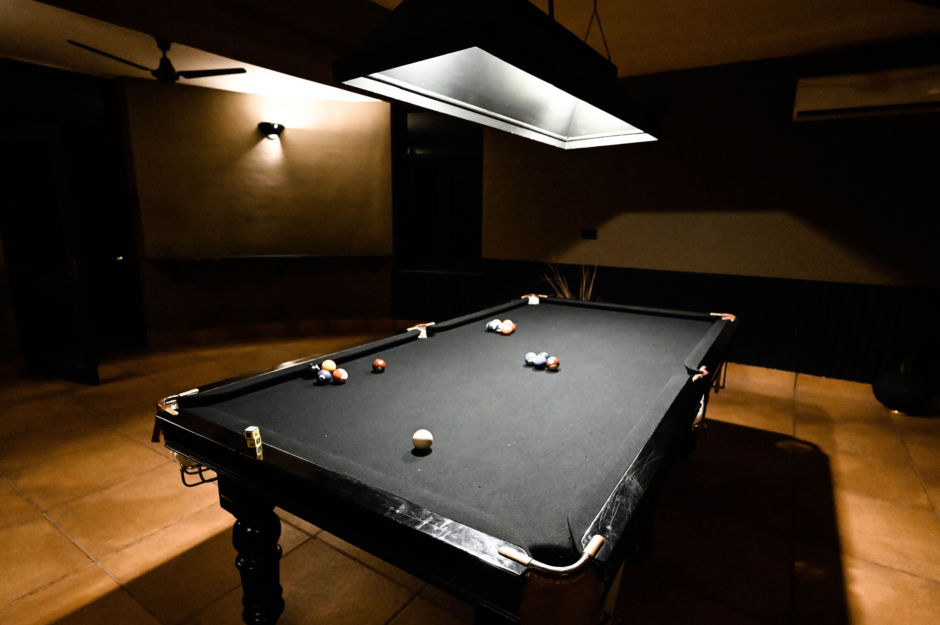 A pool table with balls, a ceiling fan, and a light fixture.
