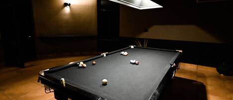 A pool table with balls, a ceiling fan, and a light fixture.
