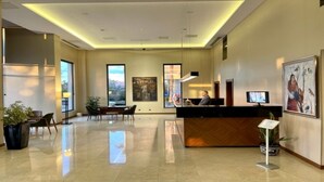 A modern hotel lobby with a reception desk, seating area, and large windows offering views. - Turkmen Riverside Hotel (Adana)