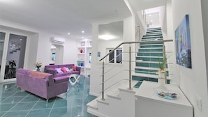 Un espace de vie moderne avec un canapé violet, un escalier et un plancher en verre.